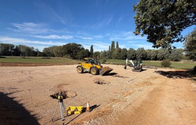 Foundation pads being dug for a new farm building on a hardcore base, with a telehandler, mini digger and laser level on site