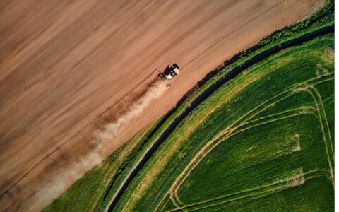 Aerial view of a tractor ploughing a field in the English countryside, Devon