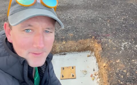 Guy French of Foxes Rural crouching beside a newly dug concrete footing with baseplate bolts for a new farm building